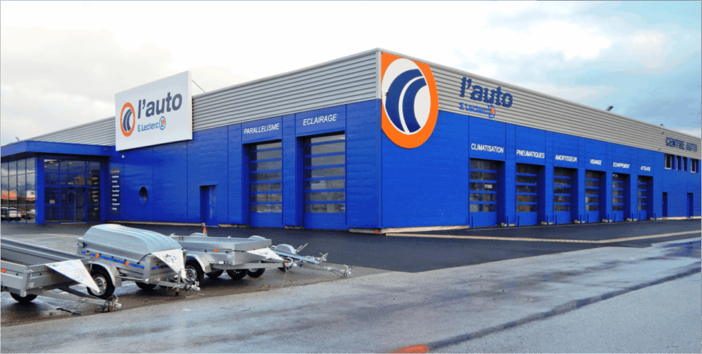 Bâtiment bleu de l'auto E. Leclerc avec remorques.