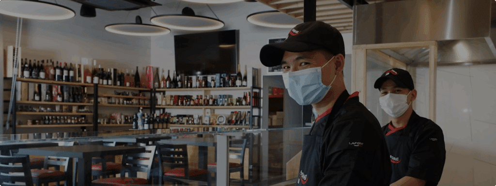 Deux chefs souriants dans un restaurant contemporain.