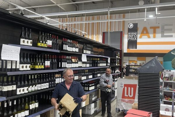 Travailleurs dans un supermarché avec des bouteilles de vin